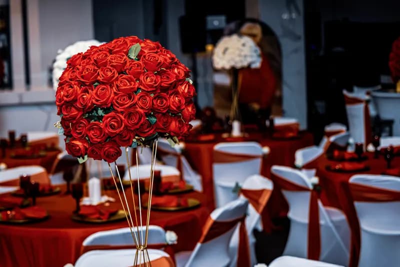 Reception with red linens, white chair covers and tall red rose centerpieces
