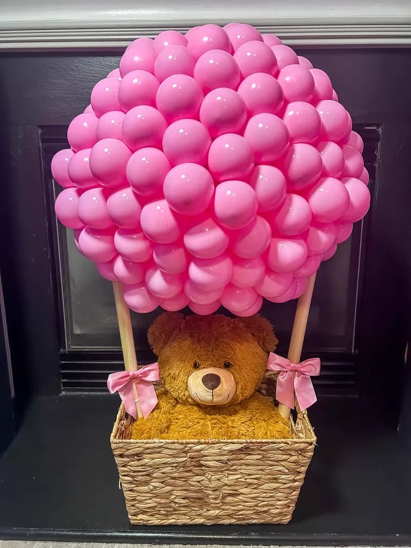 Pink balloon hot-air balloon with a teddy bear in a wicker basket