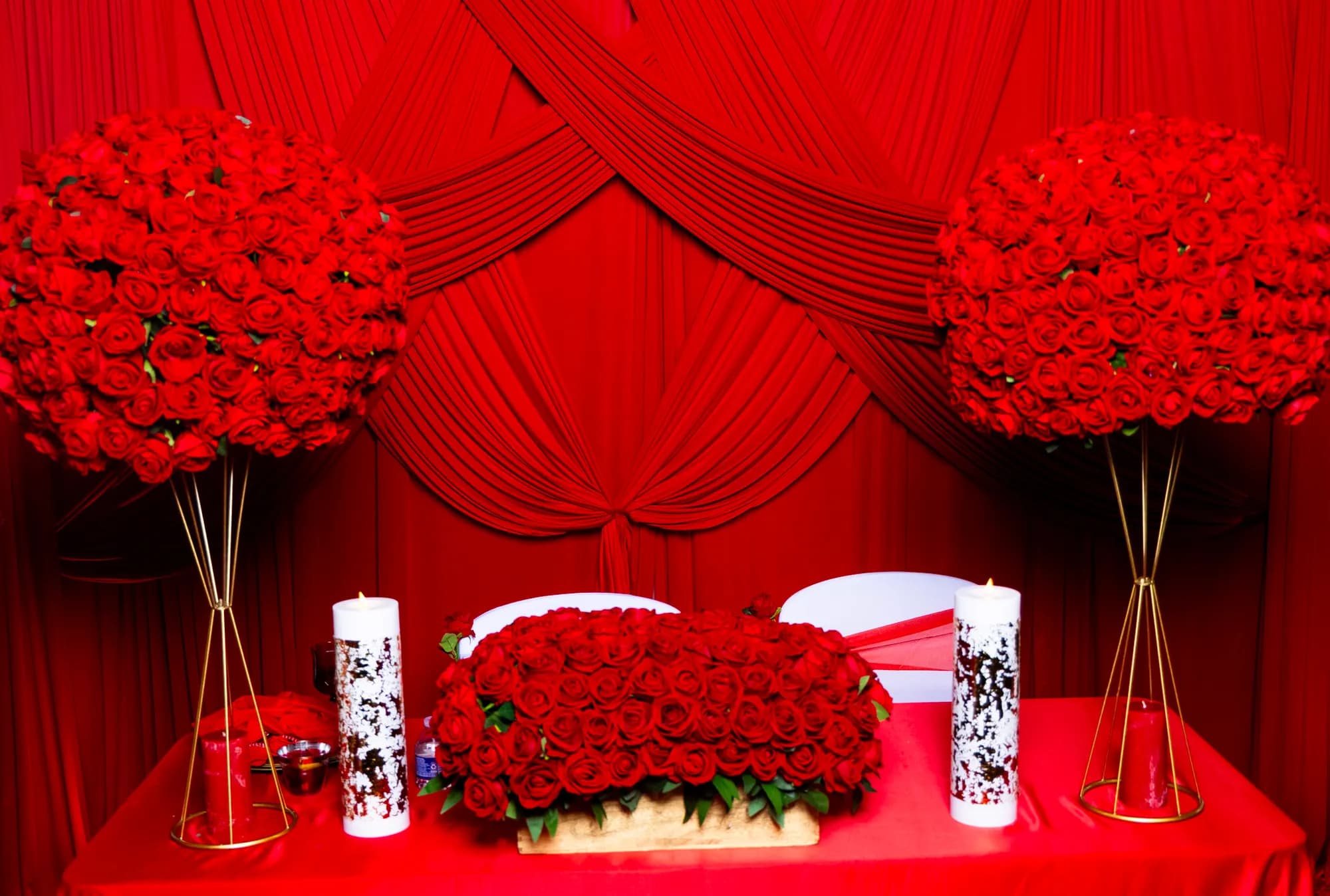 Sweetheart table with red rose ball arrangements, unity candles and red draping