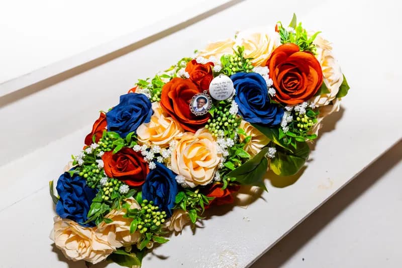 Memorial floral runner of navy, orange and peach roses with baby's breath and photo charms