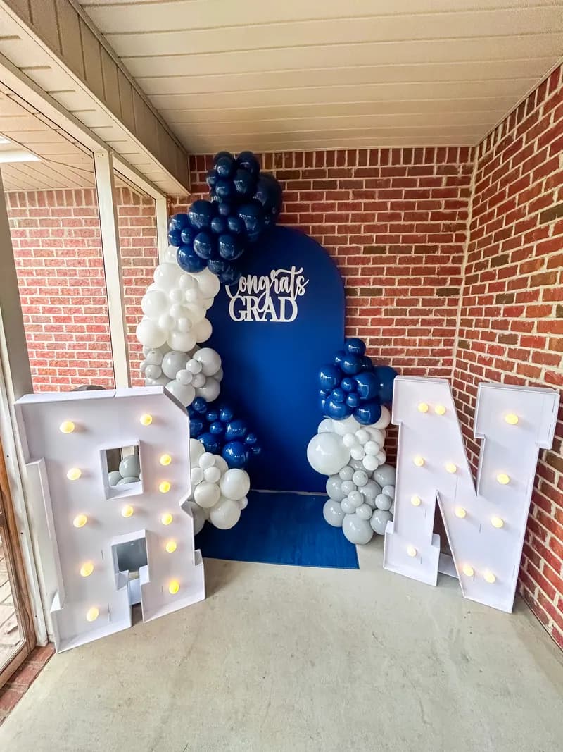 Navy 'Congrats Grad' backdrop with navy, white and silver balloon garland and marquee letters